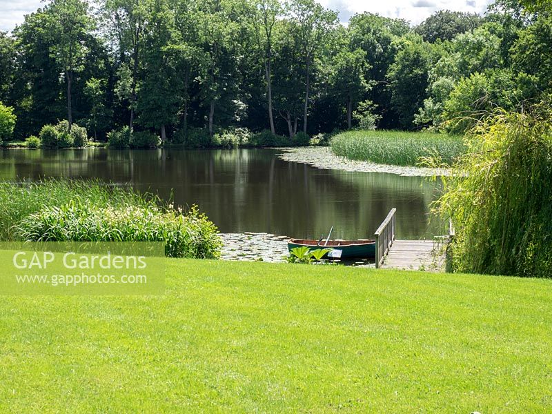 The lawn leads down to the garden lake complete with jetty and rowing boat.