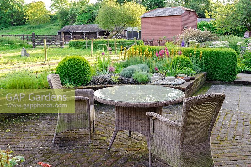 Garden table and chairs on garden terrace with view of the garden, Terstan, Stockbridge, Hants, UK. 
