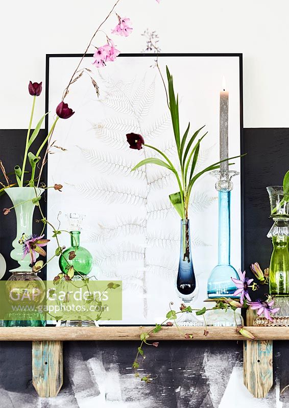 Still life on shelf with multiple vases and framed illustration. 