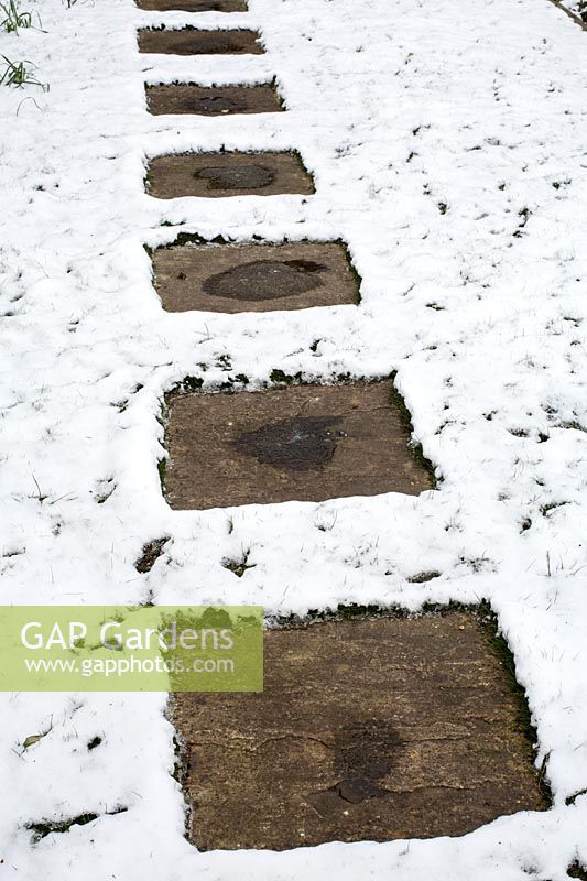 Paving stone path with snow covered lawn 