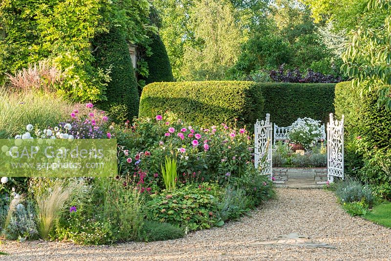 A view of an antique cast iron gateway and herbaceous border. 