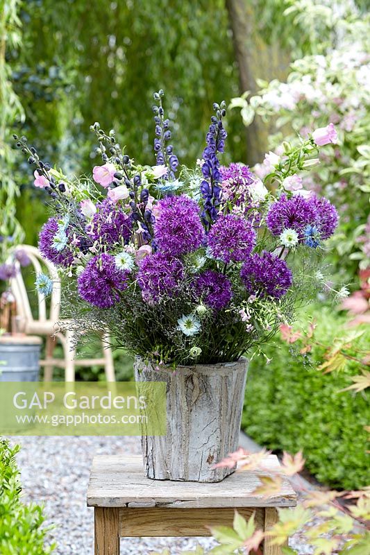 Mixed floral arrangement featuring Alliums in wooden container.