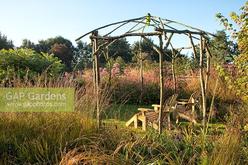 Rustic gazebo at Ellicar Gardens, Nottinghamshire with perennial borders