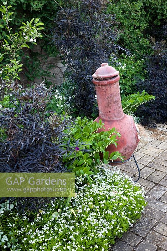A view of a clay chiminea in the corner of the patio. 