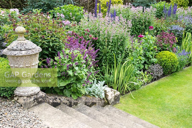 Herbaceous border with lawn stone steps and old stone urn, Scotland â€‰ 