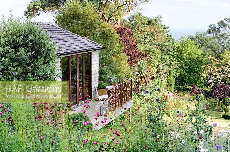 View of garden studio surrounded by flowering beds and borders. 