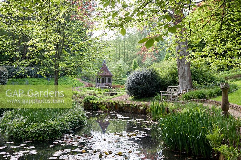 View of pond and surrounding trees with summerhouse in the distance. 