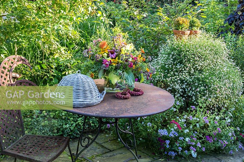 A metal table set with summer bouquet and wicker tray cover. 