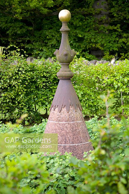 A salvaged cast-iron finial creates focal point in garden. 