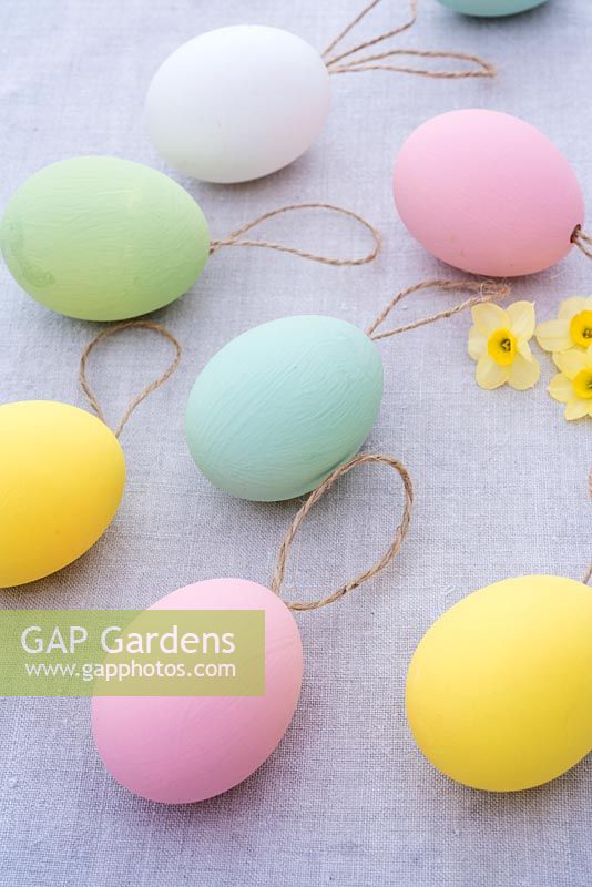 Pastel coloured easter eggs with string on linen background