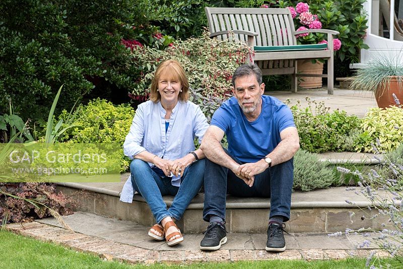 Woman and man sitting on patio steps planted with herbs