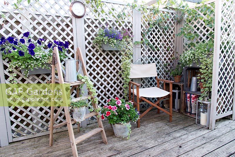 Trellis screening is a backdrop for pots and accessories on decked area. 