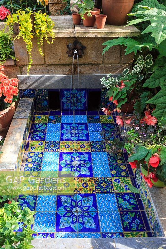 Moroccan-style fountain area surrounded by potted plants