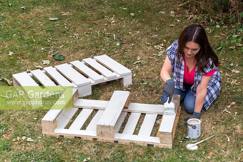 Painting a wooden pallet white.