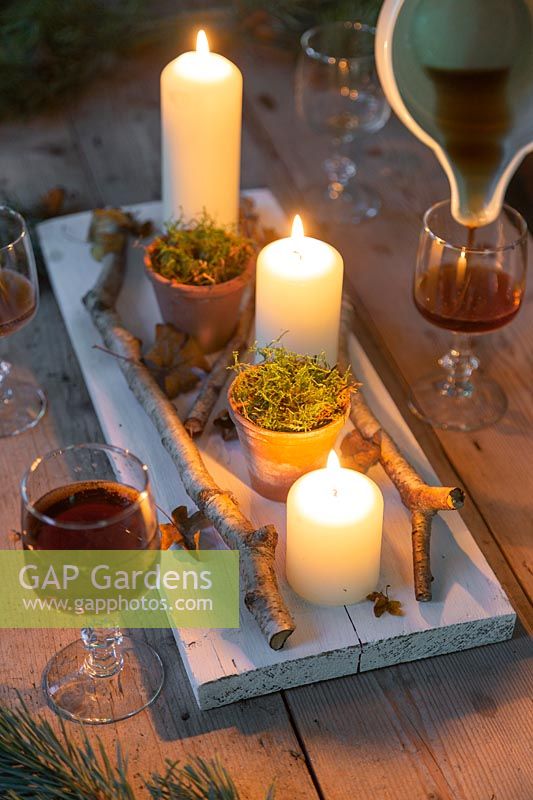 Rustic table centerpiece with birch twigs, autumnal leaves and terracotta pots filled with moss. 