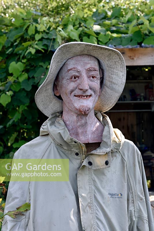 Lifelike male Scrawcrow dressed in old clothes and wearing hat, Golf Course Allotments, London, UK. 
