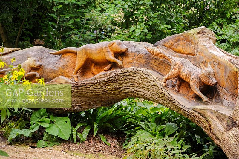Felled oak carved with a hunting scene on one side, by chainsaw sculptor Matthew Crabb. Abbotsbury Subtropical Gardens, Abbotsbury, Dorset, UK. 