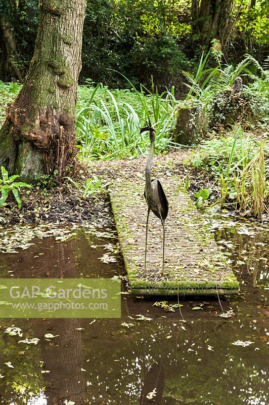 Pond with sculpture of heron with fish in its mouth, Aston Crews, Herefordshire, UK