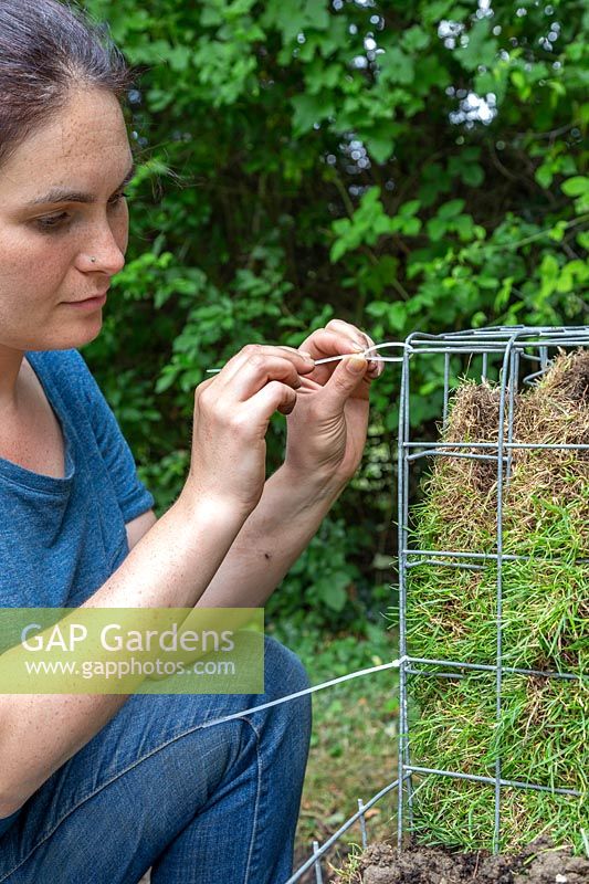 Woman using plastic cable ties to hold edges of gabion basket together