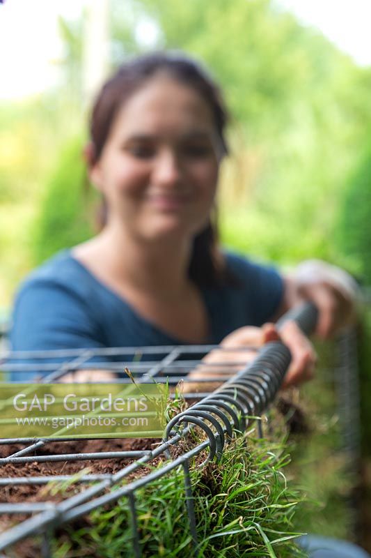 Close up detail of woman using a helical coil spring to secure lid of gabion basket
