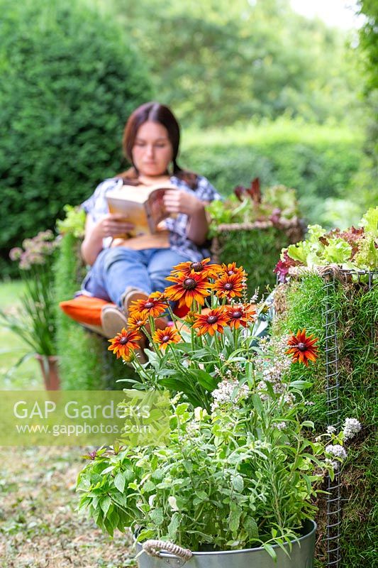 Woman relaxing and reading a book on living gabion bench