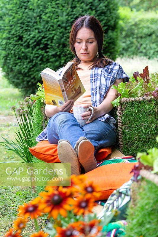 Woman relaxing and reading a book on living gabion bench