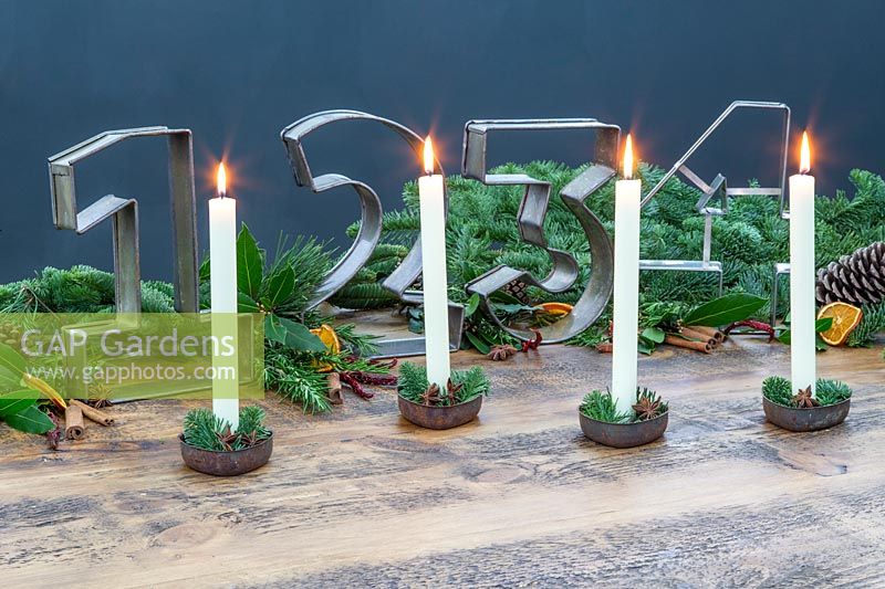 Advent table decoration with large metal number cake tins and tall white candles