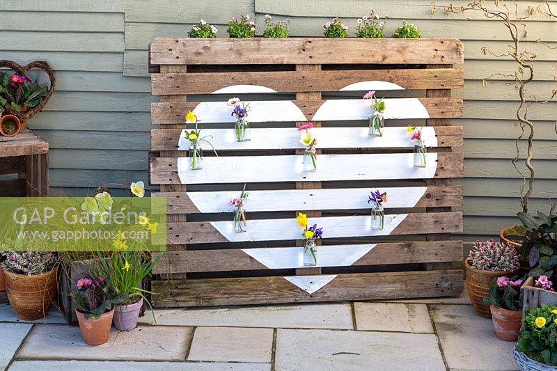 Small glass flower vases hanging on pallet with white heart