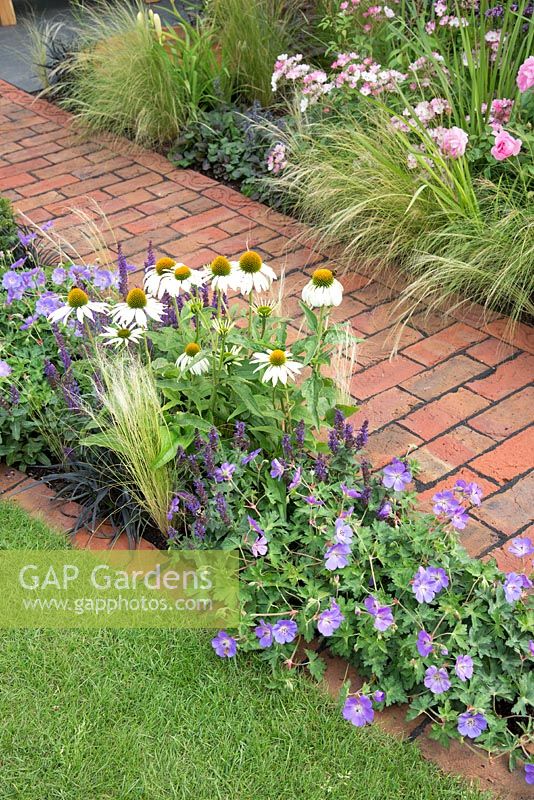 Flowering perennials bordering brick path in 'A Place to Ponder' garden. Designed by Matt Haddon, RHS Tatton Park Flower Show, 2018. 