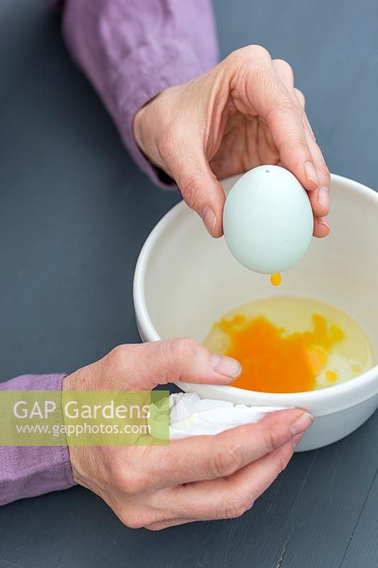 Woman blowing the content of the egg into a bowl leaving the shell empty