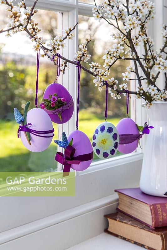 Decorated Easter eggs hanging on branches in windowsill