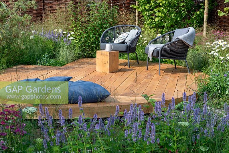 Outdoor seating on oak decking with floor cushions, Agastache 'Blue Fortune' in the foreground - Raised by Rivers, RHS Tatton Park Flower Show 2018