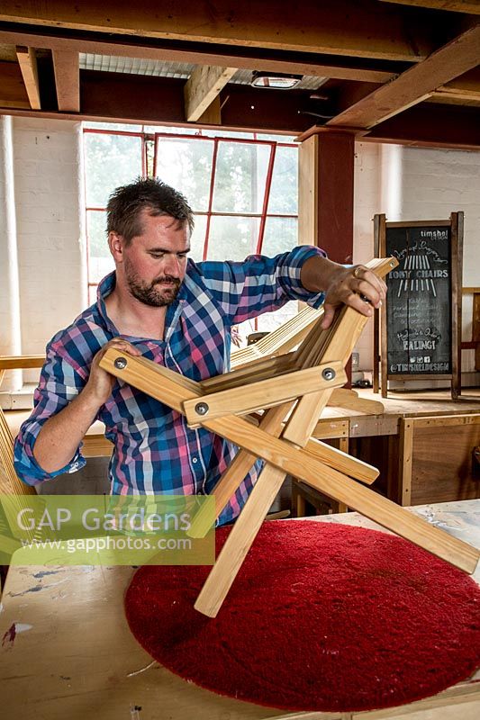 Chris Punch, garden furniture designer in workshop assembling a footstool.