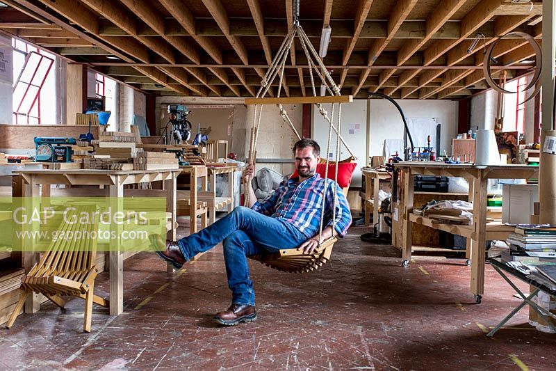 Chris Punch, garden furniture designer in his workshop, with the range of chairs he produces