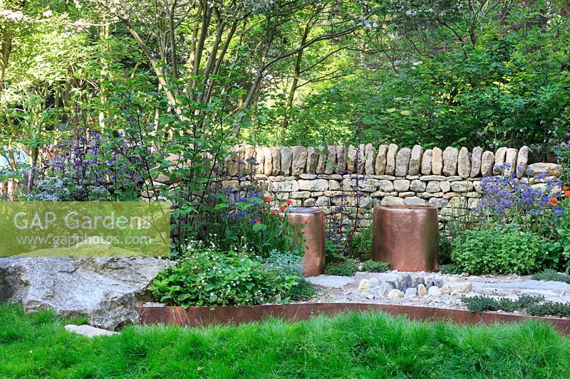The Warner Edwards Garden, copper seats and fire-pit, backed by a drystone wall and mixed planting - RHS Chelsea Flower Show, 2018