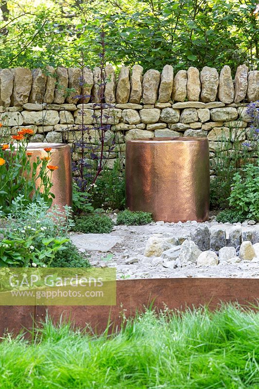 Copper seating surrounded by a dry stone wall. The Warner Edwards Garden, a representation of Falls Farm in the Northamptonshire countryside, Sponser: Warner Edwards, RHS Chelsea Flower Show, 2018.