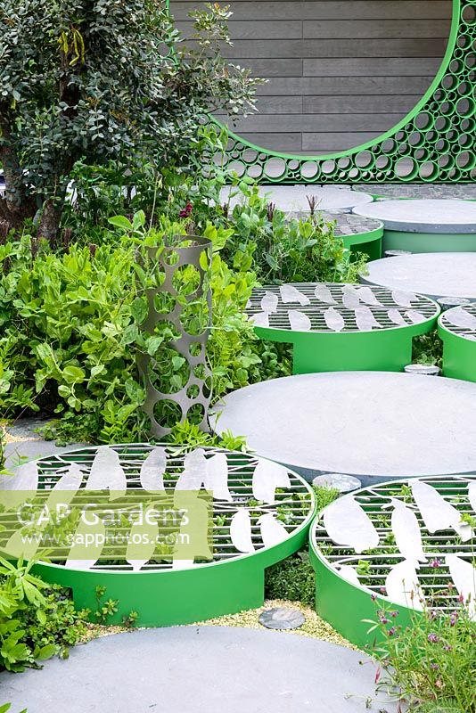 Path made of circular stepping stones with metal grates with pea shapes - The Seedlip Garden - Sponsor: Seedlip - RHS Chelsea Flower Show 2018