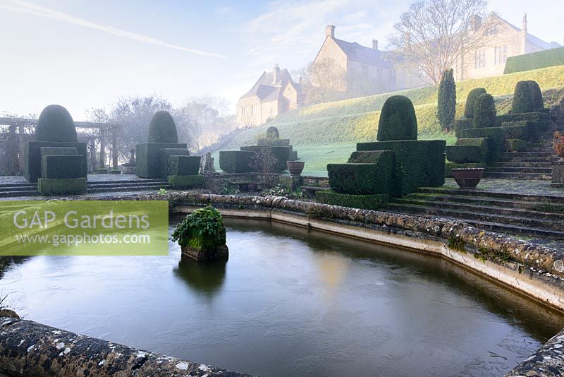 Clipped yews and decorative urns at The Fountain Court on a winter's morning at Mapperton, Dorset, UK 