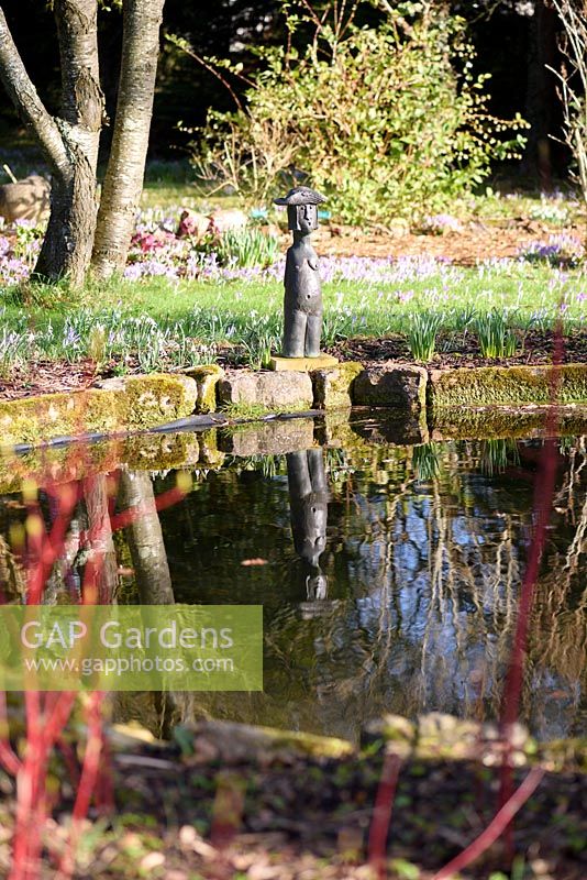 Statuette of naked female figure with hat beside the pond at The Down House, Hampshire in winter. 