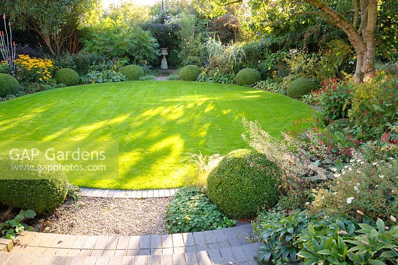 Circular lawn with beds of herbaceous perennials, clipped Box and grasses - Shropshire, UK