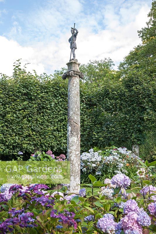 Tall, stone column in Hydrangea garden, surmounted by lead, classical figure