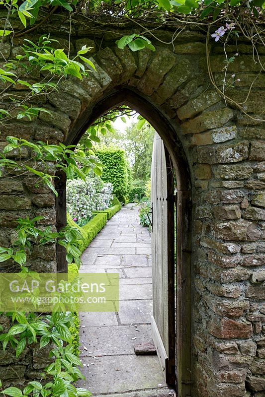 View through gothic archway to formal gardens beyond at Watcombe, Somerset, UK. 