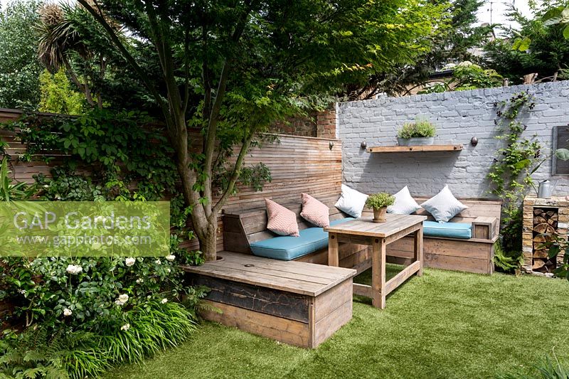 Courtyard garden in West London with artificial lawn and reclaimed Scaffold board seating 