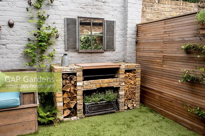 Courtyard garden in West London with brick barbecue, wall mirror and Cedar battened Trellis