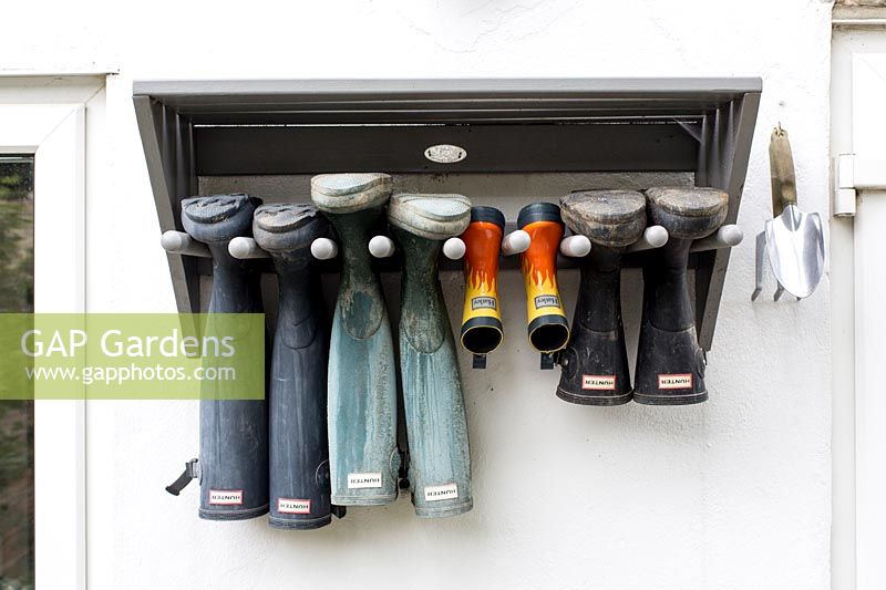 Adult and children's wellington boots hanging from wall mounted rack 