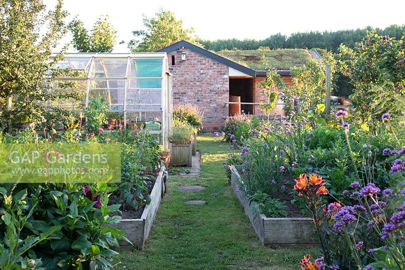 Kitchen garden with rasied beds planted with vegetables and flowers for cutting greenhouse and adjacent paddock with stable  â€‰  â€‰