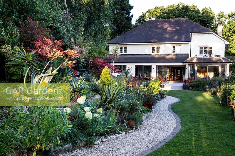 Mixed planted borders with house - Pam Woodall's garden, 'Pinecombe' in Dorset, UK