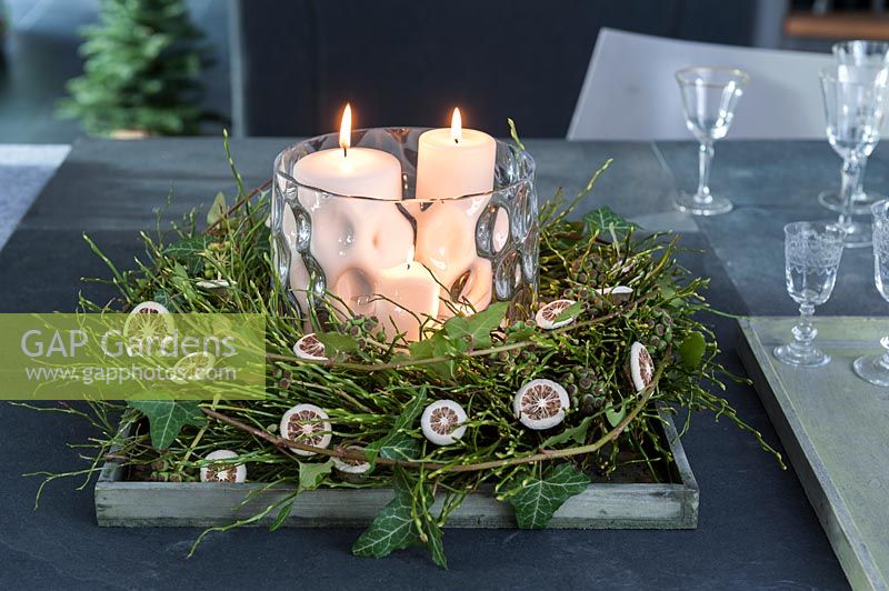 Vaccinium myrtillus wreath and ivy cirrus with infructescence -  dried lemons 
with 2 white candles in a lantern