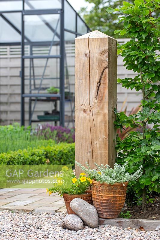 Wooden post in garden as finale for hedge