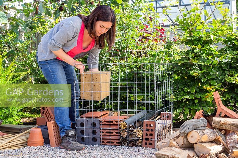 Woman adding wood block with holes into wire cage